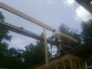 Carpenter setting a ridge beam over a new addition frame — Ice Dam Removal by Roofing Brothers in Voorheesville