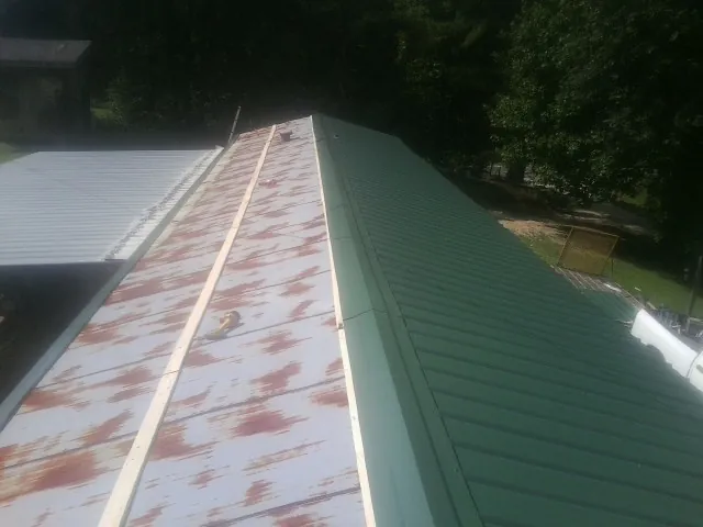 Old rusted panels beside newly installed green metal roofing — Wind Damage Roof Repair by Roofing Brothers in Voorheesville