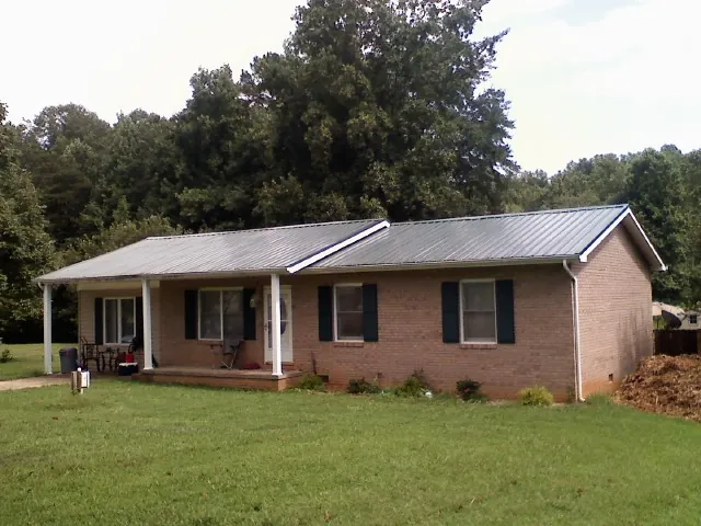 Gray metal roof on a brick ranch house with a side carport in Voorheesville