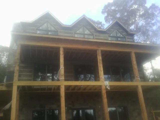 Dormers and porch framing on a large log home under construction — Roof Coating work by our crew in Voorheesville