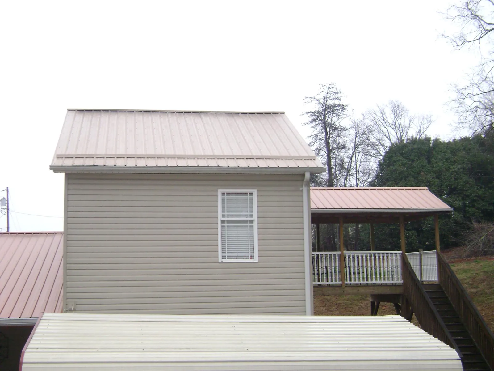 Tan metal roofs on a two story addition and attached porch, from a Roof Replacement job in Voorheesville