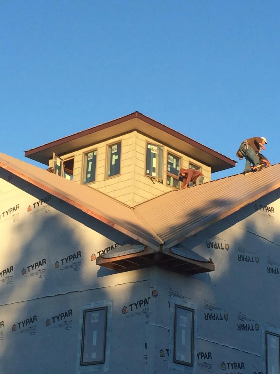 Roofers working around a rooftop cupola on a new metal roof at sunset — Roof Waterproofing in Voorheesville by Roofing Brothers
